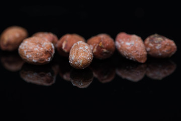 Fototapeta premium Salted roasted peanuts close up macro shot on shiny black surface, space for text.