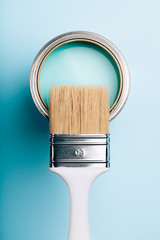Brush with white handle on open can of turquoise paint on blue pastel background. Renovation concept. Macro. - 237409089