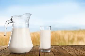 Glass jug of fresh milk  on background