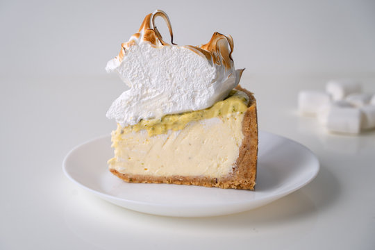 Lemon meringue cheesecake on white plate on white background