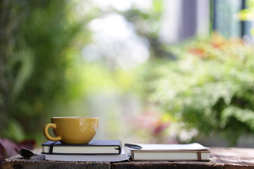 Yellow ceramic cup with notebooks at on wooden table 