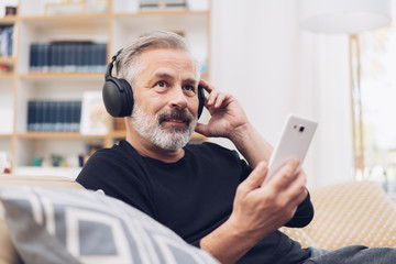Middle-aged man listening to music online at home - obrazy, fototapety, plakaty