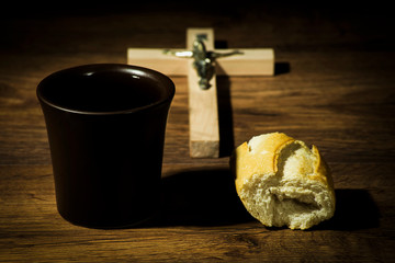 The concept of the multiplication of bread and wine in the Christian religion, bread and a cup of wine against the background of the cross
