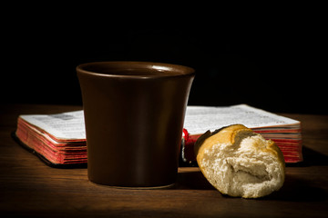 The concept of the multiplication of bread and wine in the Christian religion, bread and a cup of wine on the background of the book for prayer