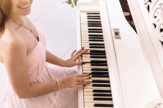 Closeup of a young woman in a pink dress playing the piano