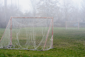 Old empty abandoned football field  and gate with a tangled net in a light fog