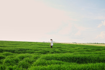 A man alone in a green field, breathing air goes through the field