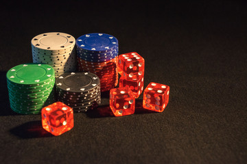 dice and poker chips on black background