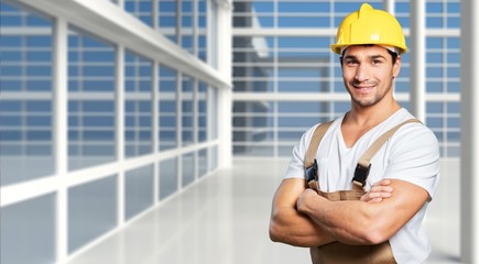 Young builder in hardhat on blurred construction materials store