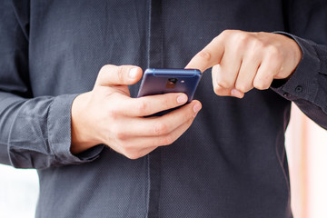 Man using mobile smartphone - focus on top of the phone
