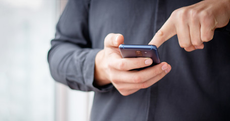 Man using mobile smartphone - focus on top of the phone