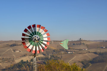 Domestic wind blade in the colors of the Italian flag with the Piedmont hills in the background in autumn, Alba, Italy