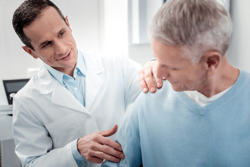 Fototapeta premium Positive delighted doctor doing massage on shoulder