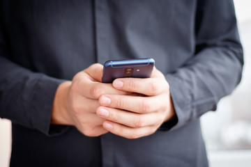 Male hand holding a cell smartphone and writing sms