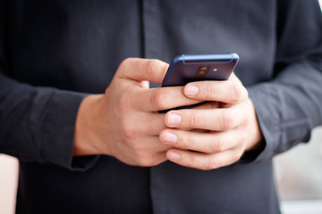 Male hand holding a cell smartphone and writing sms
