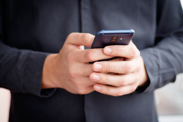 Male hand holding a cell smartphone and writing sms