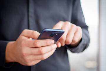 Male hand holding a cell smartphone and writing sms