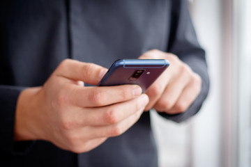 Male hand holding a cell smartphone and writing sms