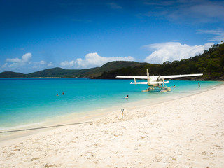 A white beach, turquoise water a water airplane and the blue sky