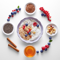 Healthy breakfast ingredients (cereals, fruits, seeds and honey) arranged in circle and various bowls. Top view