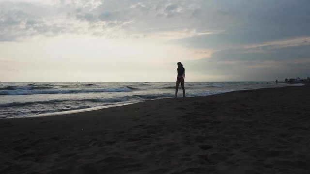 The girl walks along the beach at sunset. Sea, sunset, relax. Vacation