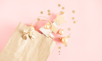 Christmas elegant composition. Paper bag and gift with gold ribbon on pastel pink background. Christmas, New Year, winter concept. Flat lay, top view, copy space
