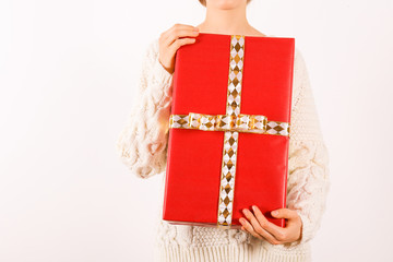 Fototapeta premium Female hands holding present with golden bow on white rustic background. Festive template for different holidays: Christmas, New Year, Birthday, Valentines day,. Close up, copy space.