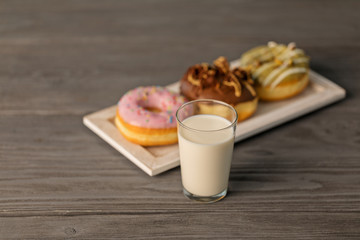 The glass of milk and doughnuts on a white tray.