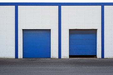 Obraz na płótnie Canvas White Industrial warehouse with blue door for trucks.