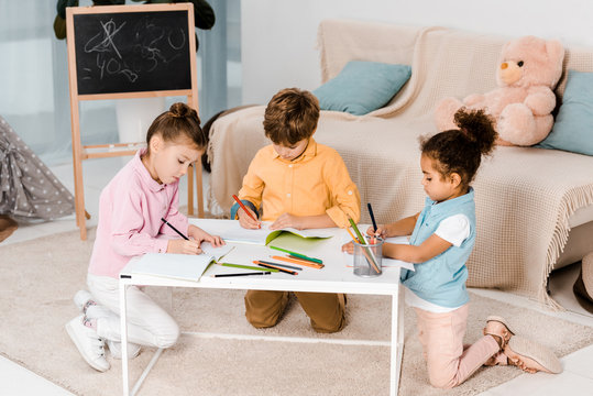 high angle view of adorable multiethnic children drawing and studying together