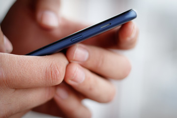 Male hand holding a cell phone and writing sms
