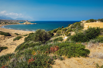 Desert coastline with sand Alagadi beach of Northern Cyprus and factory and mountains on horizon