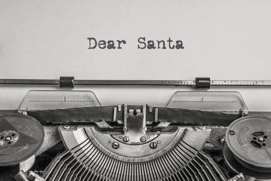 Dear Santa text typed on a vintage typewriter, black ink on old paper. A letter to Santa Claus with wishes for gifts for the New Year and Christmas