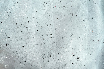 Closeup on a tulle silver and white brocade background with flecks