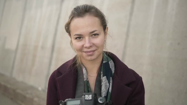 Professional young woman photographer with digital camera taking pictures with concrete slabs background. Close up, slow motion, shallow depth of field.