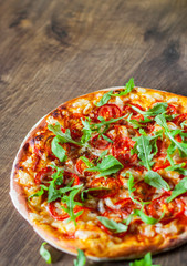 vegetarian Pizza with Mozzarella cheese, Tomatoes, pepper, Spices and Fresh arugula. Italian pizza. Pizza Margherita or Margarita on wooden table background