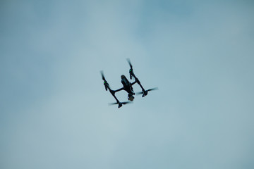 Drone flying overhead in cloudy blue sky