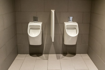 Two white urinals in the men's room in a modern office building.