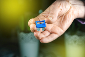 Woman hand holding blue small amp rated car fuse before inserting them fuse box closeup shot
