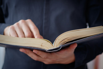 Hands folded in prayer on a Holy Bible in church concept for faith, spirtuality and religion