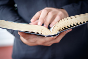 Hands folded in prayer on a Holy Bible in church concept for faith, spirtuality and religion