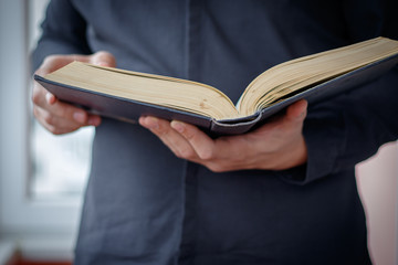 Hands folded in prayer on a Holy Bible in church concept for faith, spirtuality and religion