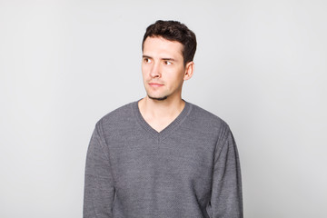 Young man wearing in grey sweater looking to the right