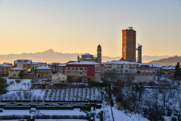 Obraz premium View of the snow covered village of Barbaresco with the medieval tower and Alps mountains at sunset in winter, Barbaresco, Langhe, Piedmont, Italy