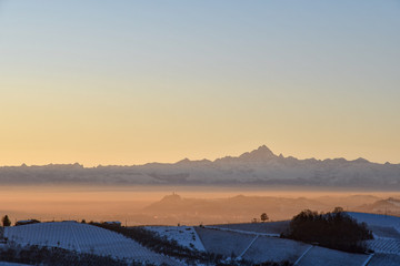 Scenic view of a snow covered landscape with hills and Alp mountains at sunset in winter, Barbaresco, Langhe, Piedmont, Italy