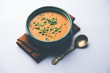 Green Peas curry / Matar masala served in a bowl over moody background. selective focus