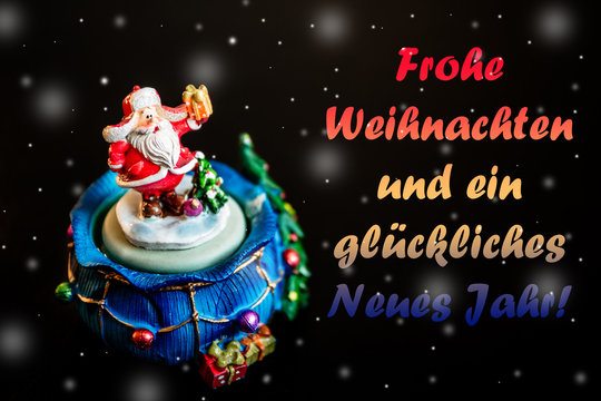 Cute toy Santa Claus isolated on black background with snowflakes and color inscription Frohe Weihnachten und ein gutes neues Jahr in German