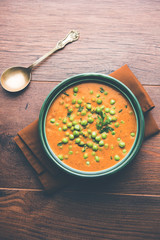 Green Peas curry / Matar masala served in a bowl over moody background. selective focus