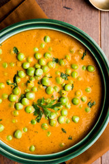 Green Peas curry / Matar masala served in a bowl over moody background. selective focus