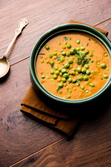 Green Peas curry / Matar masala served in a bowl over moody background. selective focus